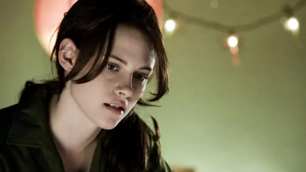 HD desktop wallpaper featuring Kristen Stewart with a pensive expression, set against a softly lit background with blurred lights.