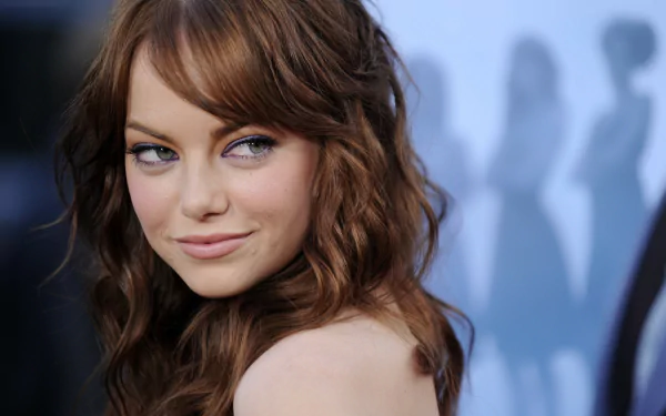 A stunning HD desktop wallpaper featuring actress Emma Stone, showcasing her playful expression and beautiful, wavy red hair against a softly blurred background.
