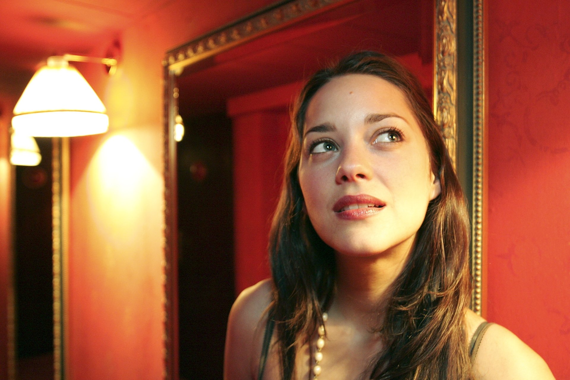 Celebrity actress portrait in a warm red-lit room, gazing upward; 2K Quad HD PC desktop wallpaper/background.