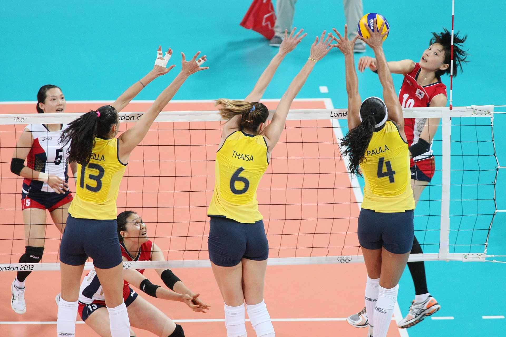 A dynamic volleyball match with players in action, showcasing teamwork and athleticism against a vibrant blue background, making it a striking HD desktop wallpaper.