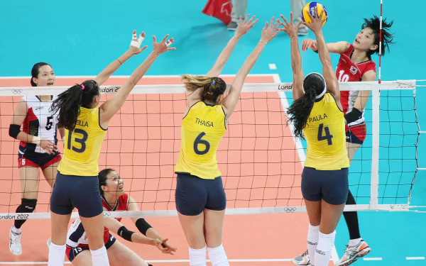 A dynamic volleyball match with players in action, showcasing teamwork and athleticism against a vibrant blue background, making it a striking HD desktop wallpaper.