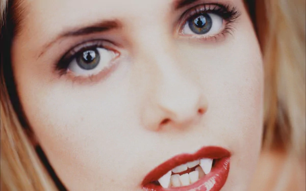 Close-up HD desktop wallpaper of Sarah Michelle Gellar as Buffy from the TV show Buffy the Vampire Slayer, showcasing her vampire fangs and intense gaze.
