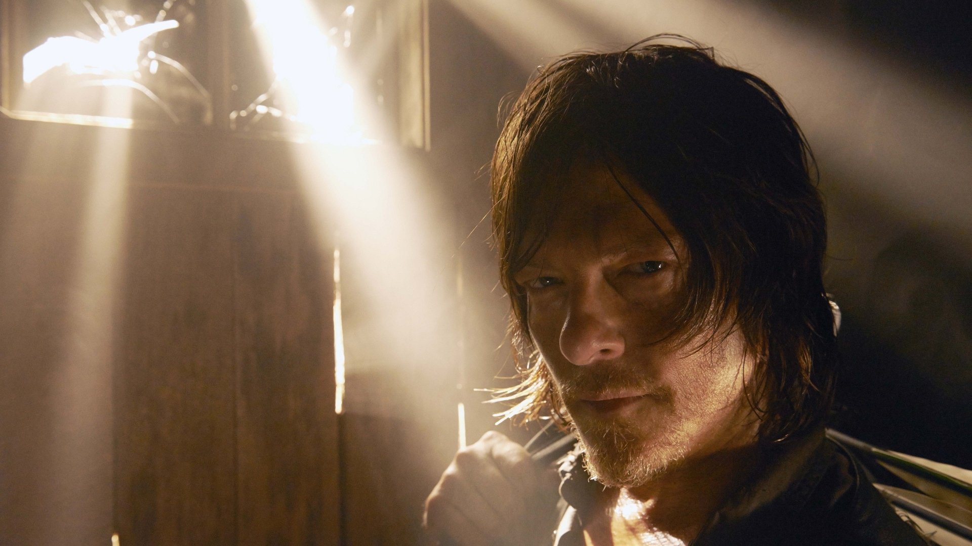Daryl Dixon, portrayed by Norman Reedus in The Walking Dead, is featured with dramatic lighting, creating an intense atmosphere for this HD desktop wallpaper.