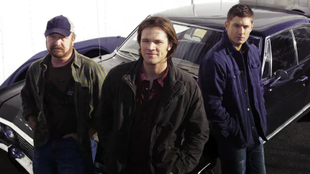 Three main characters from the TV show Supernatural pose confidently in front of a classic car, showcasing a blend of mystery and adventure in this HD desktop wallpaper.