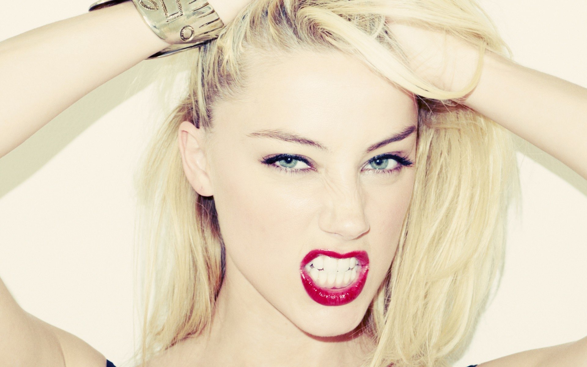 A striking HD desktop wallpaper featuring Amber Heard with bold red lips and intense blue eyes, showcasing a fierce expression and stylish blonde hair.