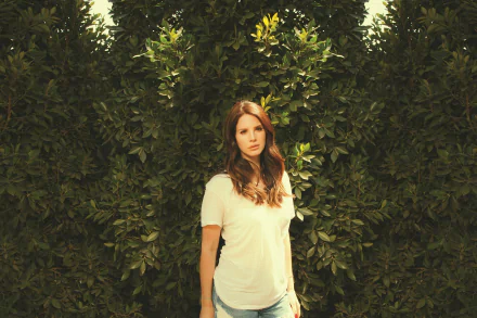 Lana Del Rey stands gracefully among lush greenery, exuding a calm and introspective vibe, perfect for a HD PC desktop wallpaper and background.