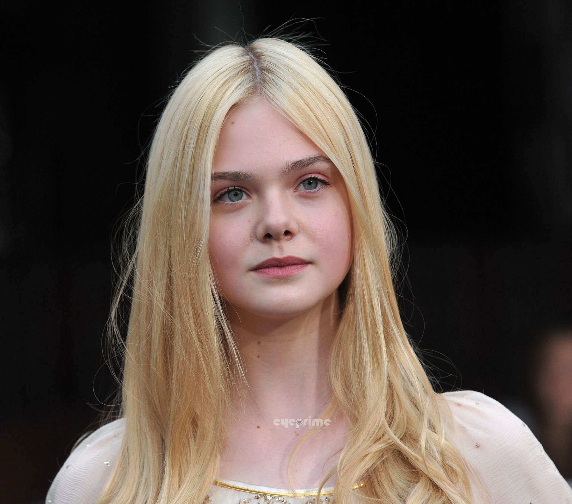 HD PC desktop wallpaper: close-up portrait of a young blonde female celebrity with long hair, soft lighting and a neutral expression against a dark background.