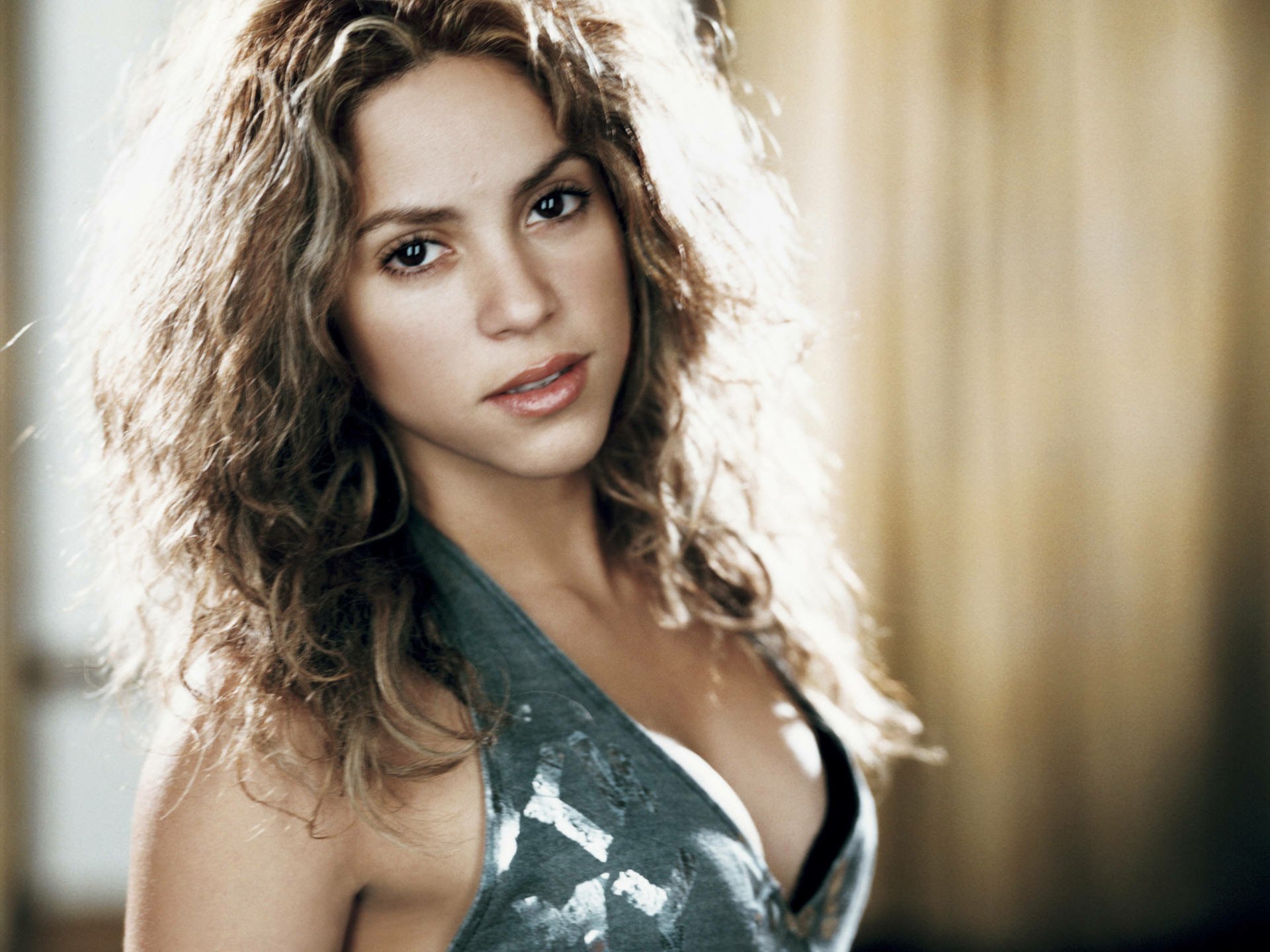 Music-themed HD PC desktop wallpaper of a female pop singer with wavy hair, wearing a halter top, gazing at the camera against a warm, softly blurred background.
