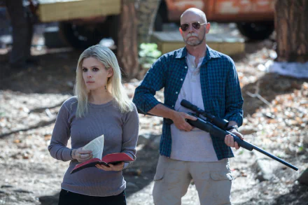 Transcendence movie 5K UHD desktop wallpaper: a woman holding a book and a man with a rifle stand together in a sunlit forest.