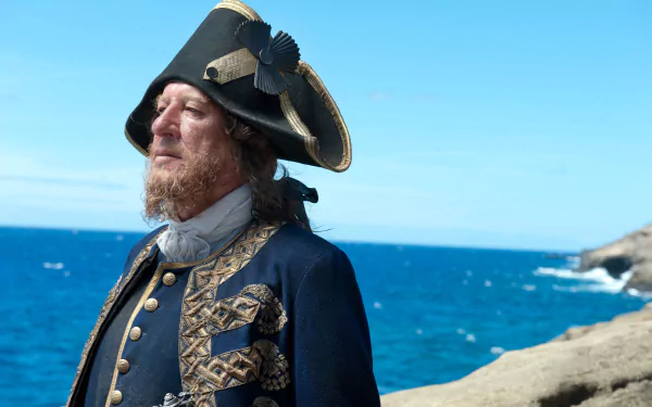 Hector Barbossa from Pirates of the Caribbean: On Stranger Tides — tricorn-hatted pirate in ornate coat, standing on seaside cliffs, 4K Ultra HD desktop wallpaper.