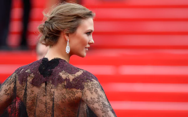 Profile of a woman in a sheer black lace gown with chandelier earrings and an elegant updo on red carpet steps — 2K Quad HD PC desktop wallpaper/background.