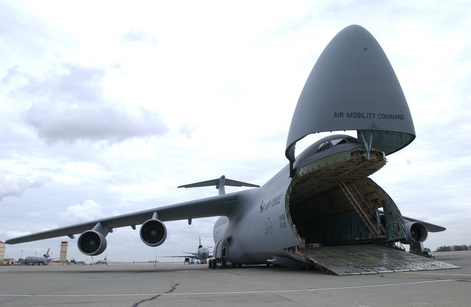 A Lockheed C-5 Galaxy military aircraft on the tarmac, showcasing its large nose that opens for cargo loading, set against a cloudy sky. A striking HD desktop wallpaper.