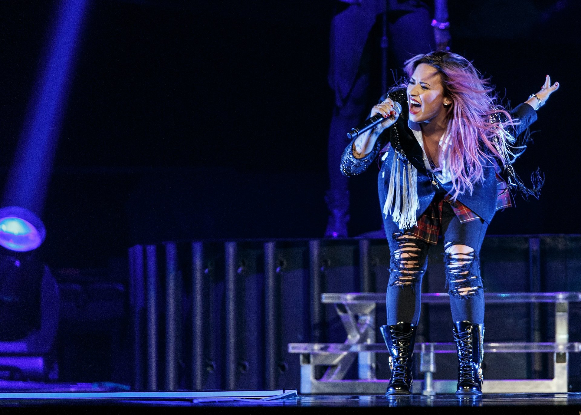 HD PC desktop wallpaper featuring Demi Lovato passionately singing on stage during a live music performance, with vibrant lighting highlighting the scene.