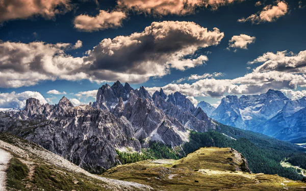Stunning HD wallpaper featuring majestic mountains under a dramatic sky, showcasing the beauty of nature with rugged peaks and lush green valleys.