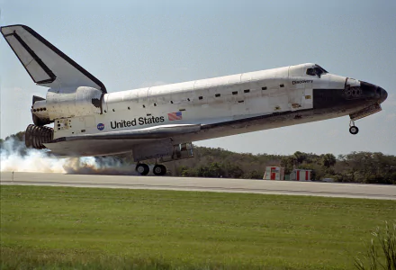 Space Shuttle Discovery from NASA lifts off, captured as a high-definition desktop wallpaper showcasing the vehicle against a clear sky and grassy runway.