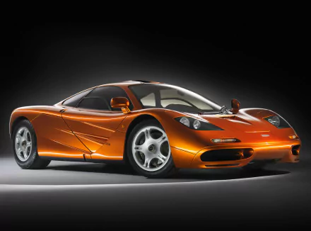 A sleek orange McLaren F1 sports car showcased as a 4K Ultra HD PC desktop wallpaper with detailed lighting and shadow effects.