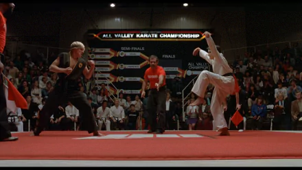 HD desktop wallpaper from the movie The Karate Kid (1984) showing the climactic All Valley Karate Championship match between two competitors in a crowded arena.