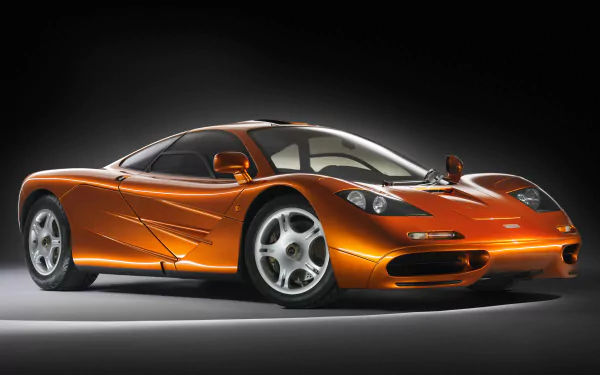 A sleek orange McLaren F1 sports car showcased as a 4K Ultra HD PC desktop wallpaper with detailed lighting and shadow effects.