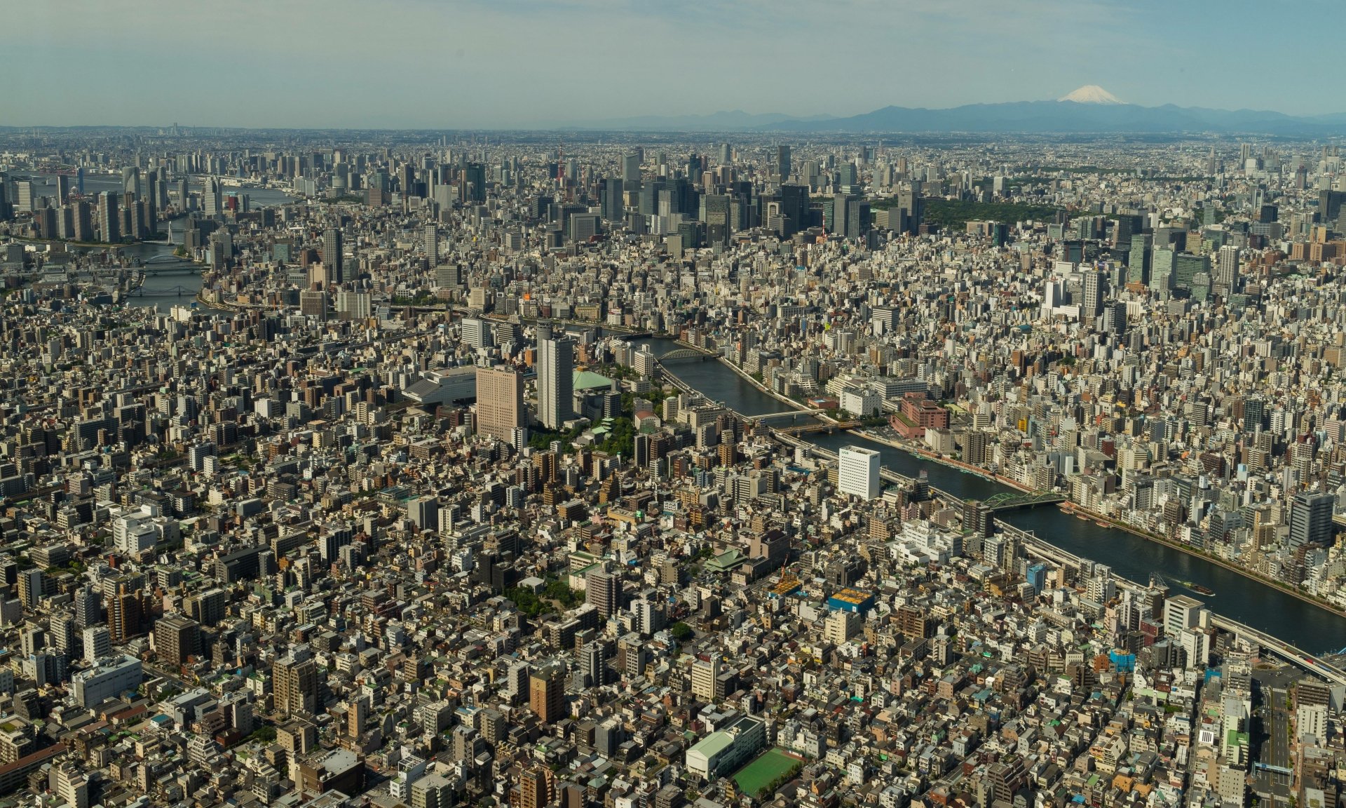 A sprawling, detailed 4K Ultra HD aerial view of Tokyo’s dense urban landscape featuring numerous buildings and a river cutting through the city.