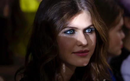 A striking HD wallpaper featuring Alexandra Daddario, showcasing her mesmerizing blue eyes and captivating expression in a beautifully lit setting.