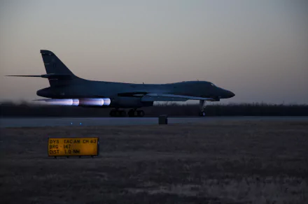 Rockwell B-1 Lancer bomber on runway at dusk with afterburners engaged, featured in a high-definition military desktop wallpaper.