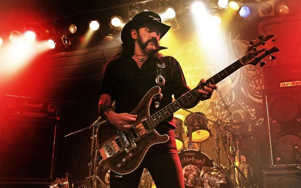 A striking HD desktop wallpaper featuring Lemmy Kilmister of Motörhead passionately playing bass on stage, illuminated by vibrant lights with a dynamic rock atmosphere.