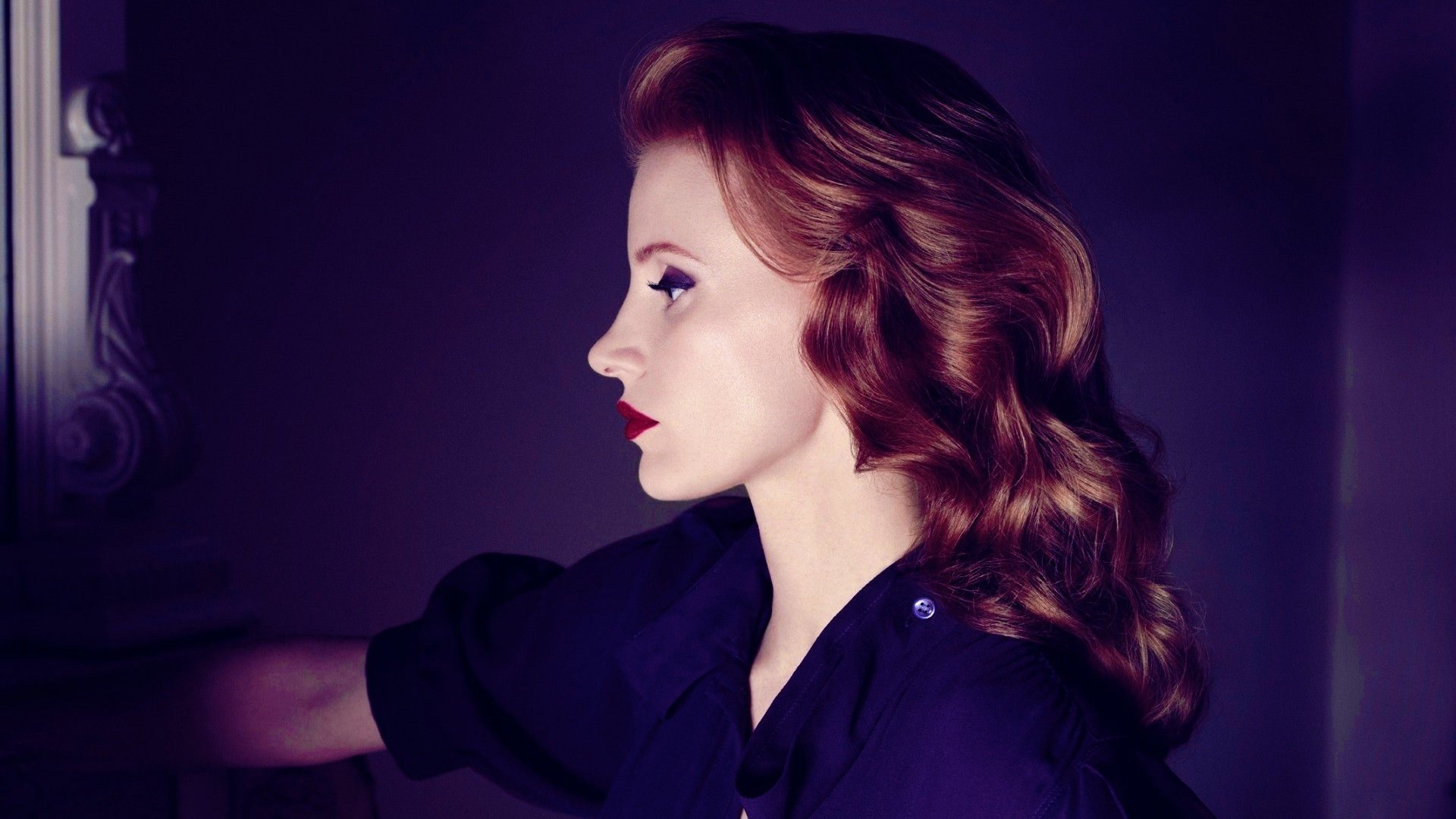 HD desktop wallpaper of a red‑haired celebrity actress in profile, vintage waves and bold red lips, dramatic side lighting against a deep purple backdrop.