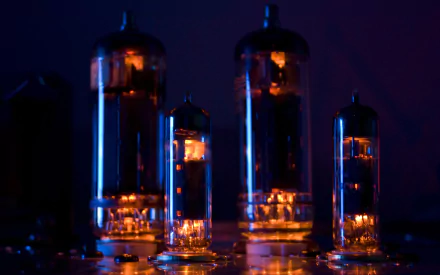 2K Quad HD PC desktop wallpaper showing close-up glowing vacuum tubes bathed in blue and orange light, evoking a retro electronics and technology aesthetic.