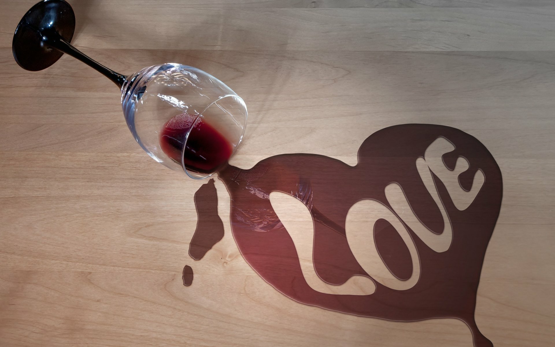 Artistic HD wallpaper featuring a spilled glass of wine forming a heart shape with LOVE written inside on a wooden background.