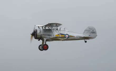 4K Ultra HD wallpaper featuring a Gloster Gladiator military biplane in flight against a gray sky.