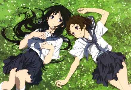 Two anime characters, Mayaka Ibara and Eru Chitanda, in school uniforms, lie on a grassy field, surrounded by greenery, from the series Hyouka. High-definition desktop wallpaper.