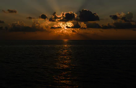 4K Ultra HD PC desktop wallpaper and background: sunset over the ocean horizon, sun piercing clouds with golden sunbeams reflecting on the water — a serene nature scene.
