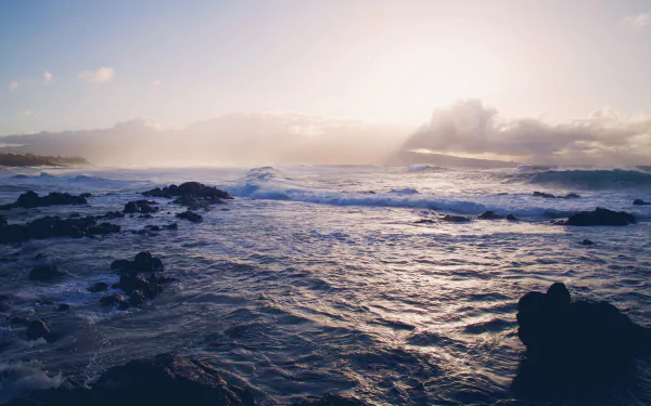 4K Ultra HD desktop wallpaper of ocean waves crashing against rocks under a cloudy sky, capturing the dynamic beauty of nature and the sea.