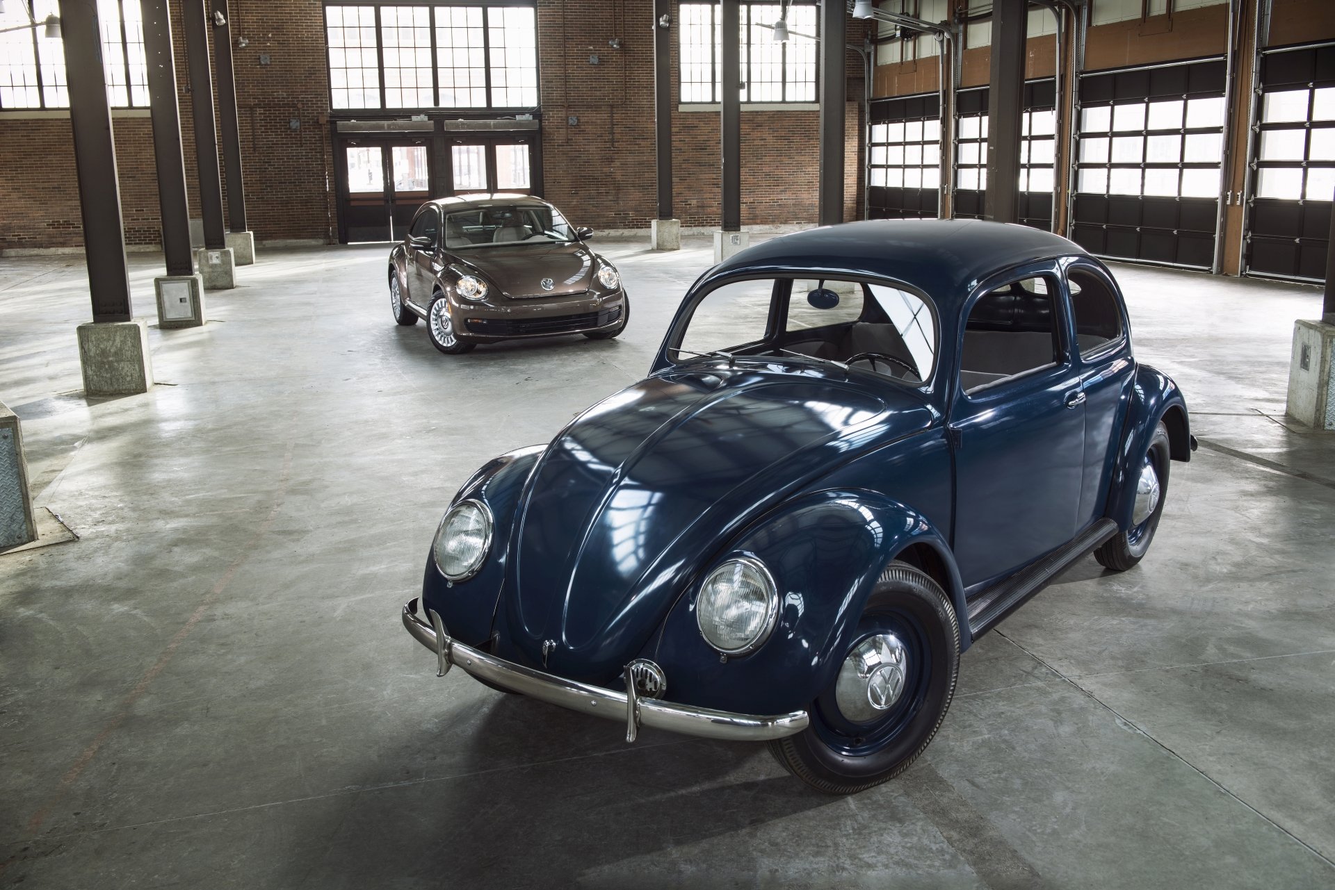 A 4K Ultra HD PC desktop wallpaper featuring two Volkswagen Beetle vehicles parked inside a spacious, industrial-style garage with large windows and exposed brick walls.