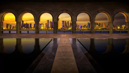 HD desktop wallpaper featuring illuminated arches framing a stunning view of Doha's cityscape at dusk, reflecting brightly on smooth water.