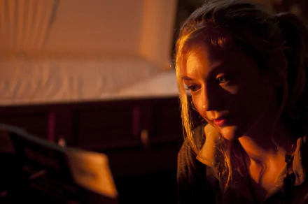 HD desktop wallpaper featuring Emily Kinney, American singer and actress, with warm lighting highlighting her contemplative expression.