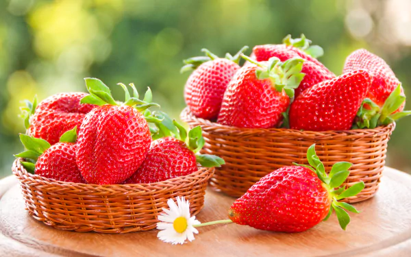 Two wicker baskets filled with fresh strawberries and a single strawberry resting on a wooden surface, captured in vibrant 4K Ultra HD detail.