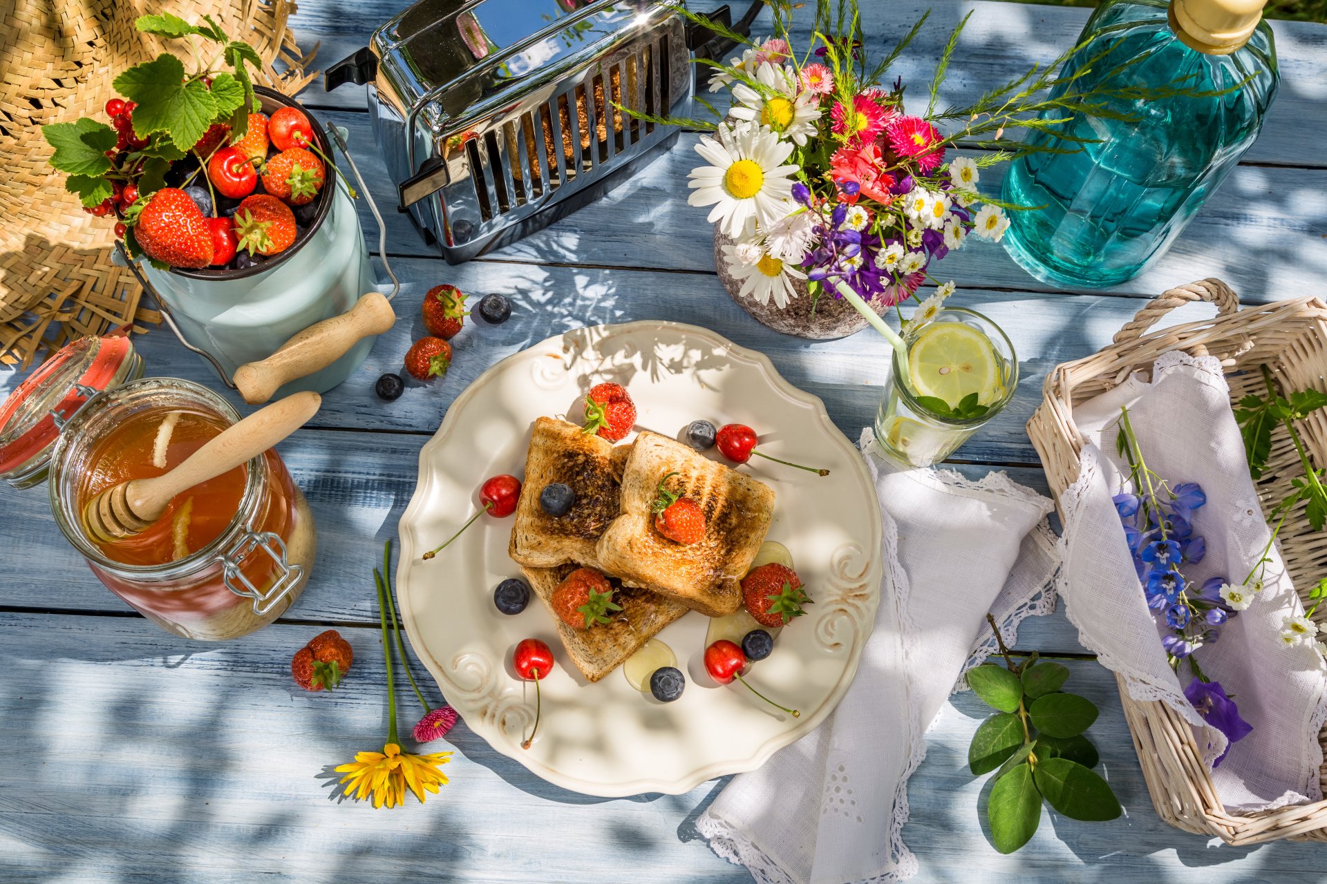 A 4K Ultra HD desktop wallpaper featuring a breakfast scene with honey-drizzled toast topped with berries, fresh strawberries, and a bouquet of flowers on a rustic table.