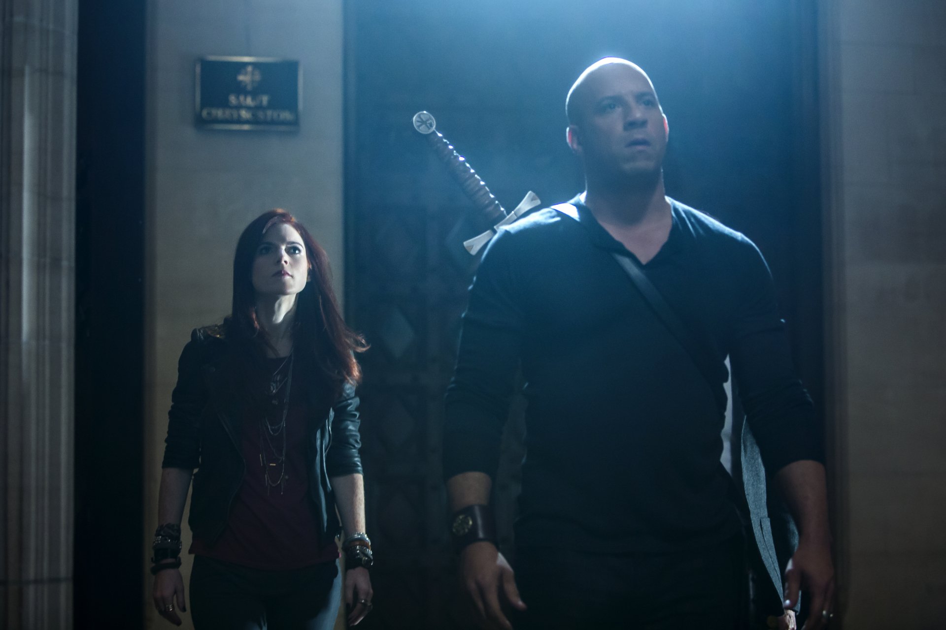 Chloe and Kaulder from The Last Witch Hunter stand together in a dimly lit scene, showcasing the film's intense atmosphere. Featuring Rose Leslie and Vin Diesel.