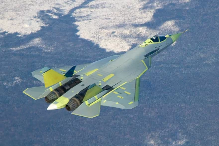 A sleek Sukhoi Su-57 jet soars through the sky, showcasing its advanced design and military technology against a backdrop of treetops and snow. An impressive HD wallpaper.