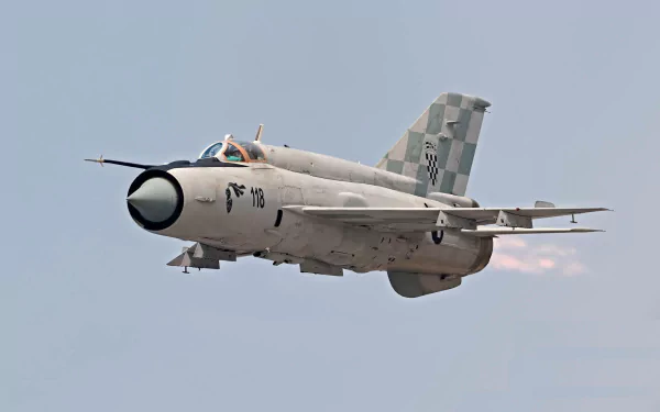 HD desktop wallpaper featuring a Mikoyan-Gurevich MiG-21 military jet in flight against a clear sky background.