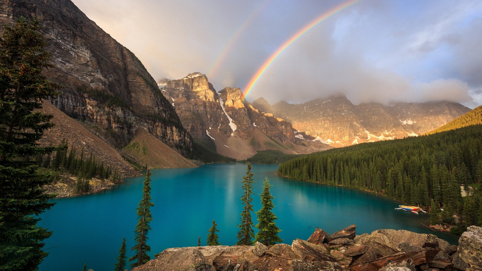 A stunning landscape featuring a vibrant rainbow arching over majestic mountains, with a serene blue lake surrounded by lush greenery, creating a captivating natural scene.