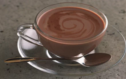 HD PC desktop wallpaper featuring a clear glass cup of rich, swirled hot chocolate on a glass saucer with a spoon, showcasing food and drink.