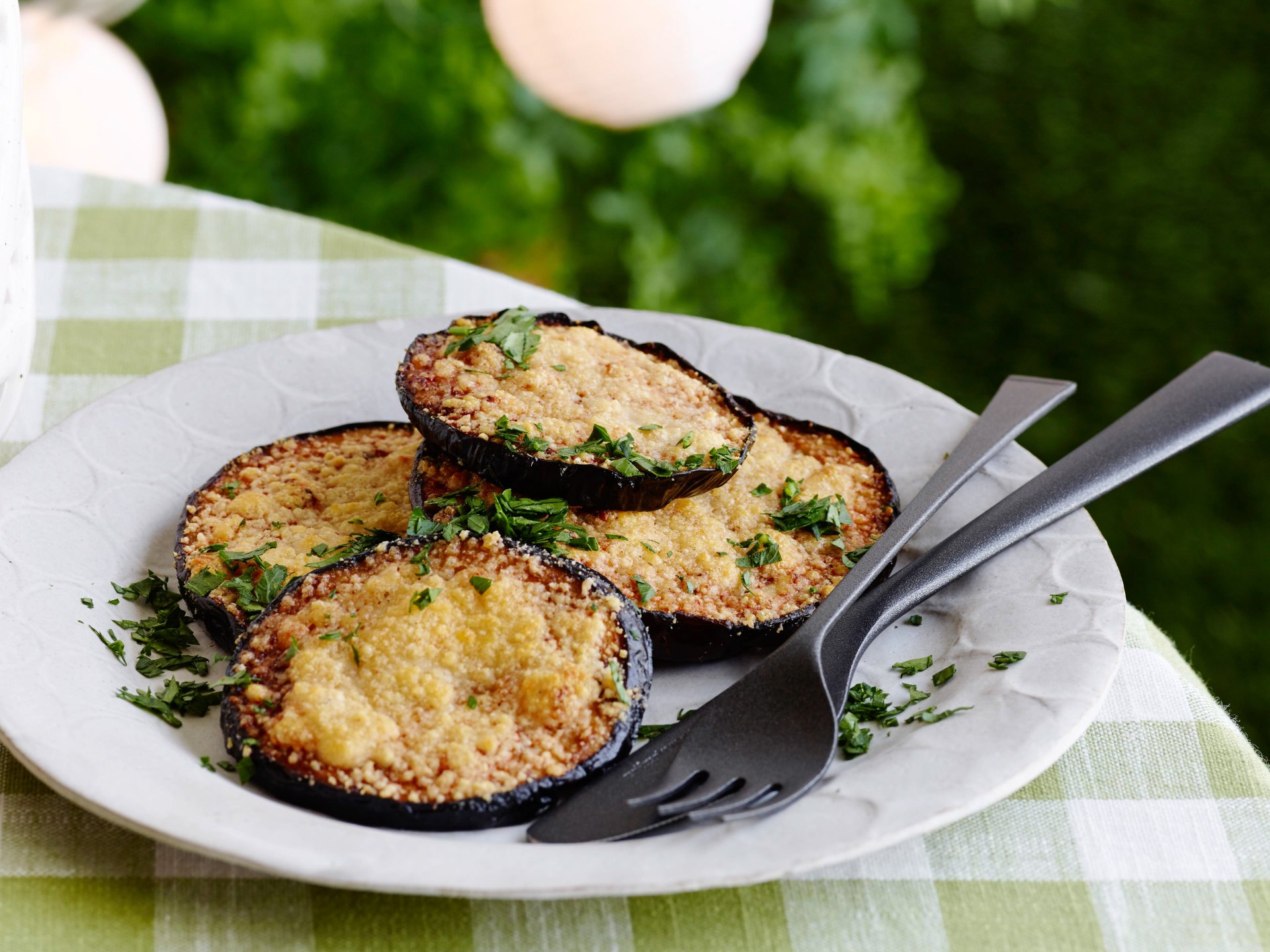 Close-up of crispy, golden-baked eggplant slices garnished with herbs on a white plate, presented in vibrant 4K Ultra HD quality for a PC desktop wallpaper background.