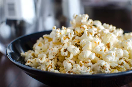 Close-up of seasoned popcorn in a black bowl, captured in 4K Ultra HD quality, serving as a vibrant PC desktop wallpaper background.