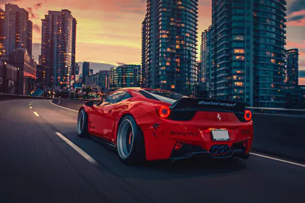 A stunning HD desktop wallpaper featuring a red Ferrari 458 driving on a city street at dusk, surrounded by modern high-rise buildings.
