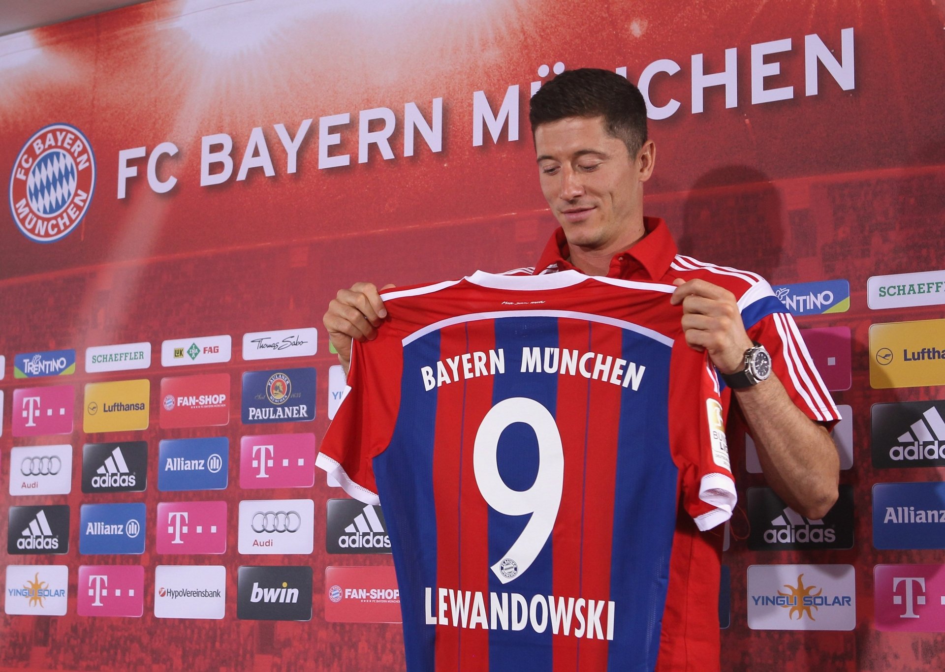 Robert Lewandowski proudly holds up his FC Bayern Munich #9 jersey. This HD desktop wallpaper captures the Polish soccer star during a significant moment in his sports career.