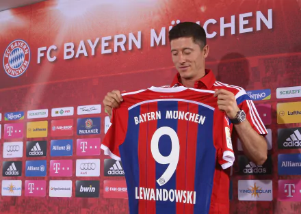 Robert Lewandowski proudly holds up his FC Bayern Munich #9 jersey. This HD desktop wallpaper captures the Polish soccer star during a significant moment in his sports career.