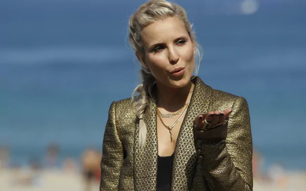 4K Ultra HD wallpaper featuring celebrity Noomi Rapace in a textured gold jacket with a serene ocean backdrop.