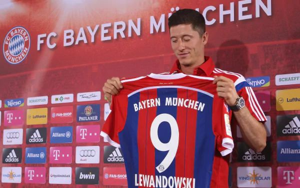Robert Lewandowski proudly holds up his FC Bayern Munich #9 jersey. This HD desktop wallpaper captures the Polish soccer star during a significant moment in his sports career.
